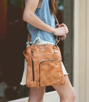 A woman holding a Bed Stu Aiken leather crossbody bag.