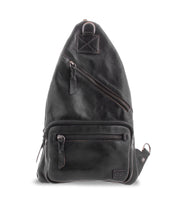 A black leather sling backpack with multiple zippers and a small loop at the top. This versatile accessory, Andie by Bed Stu, features a rectangular patch at the lower right corner, effortlessly blending practical fashion with style.