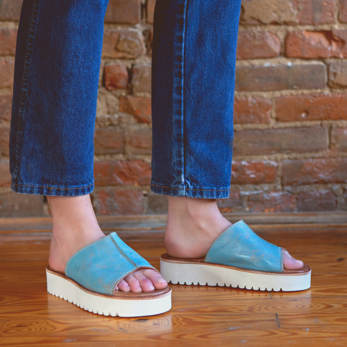 A person wearing stylish blue Fairlee II leather slide sandals from Bed Stu.