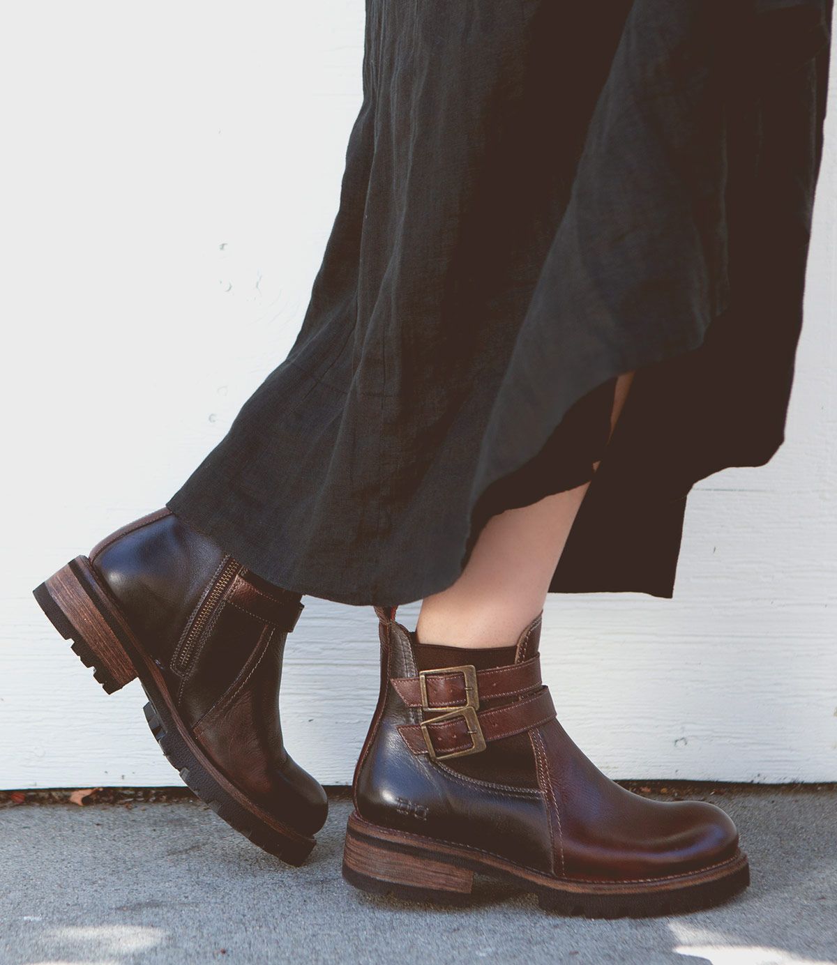 A person wearing a long dark skirt and Bed Stu's stylish Ginger II dark brown Chelsea ankle boots stands against a light-colored background.