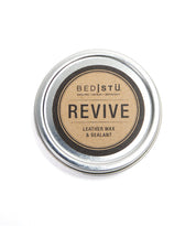 A round tin of Bed|Stü Revive Leather Care Package, labeled in black and gold on a white background.