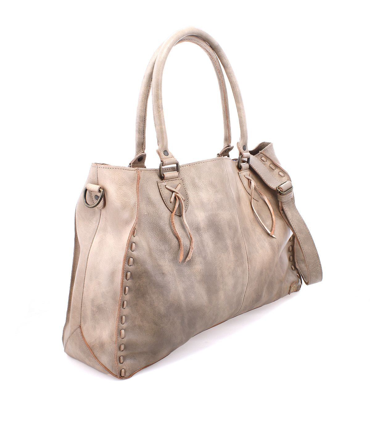 The Rockaway by Bed Stu is a spacious beige leather handbag with two handles, side detailing, and a zip-pocket divider for versatile storage. Equipped with an optional shoulder strap, it effortlessly blends style and functionality.