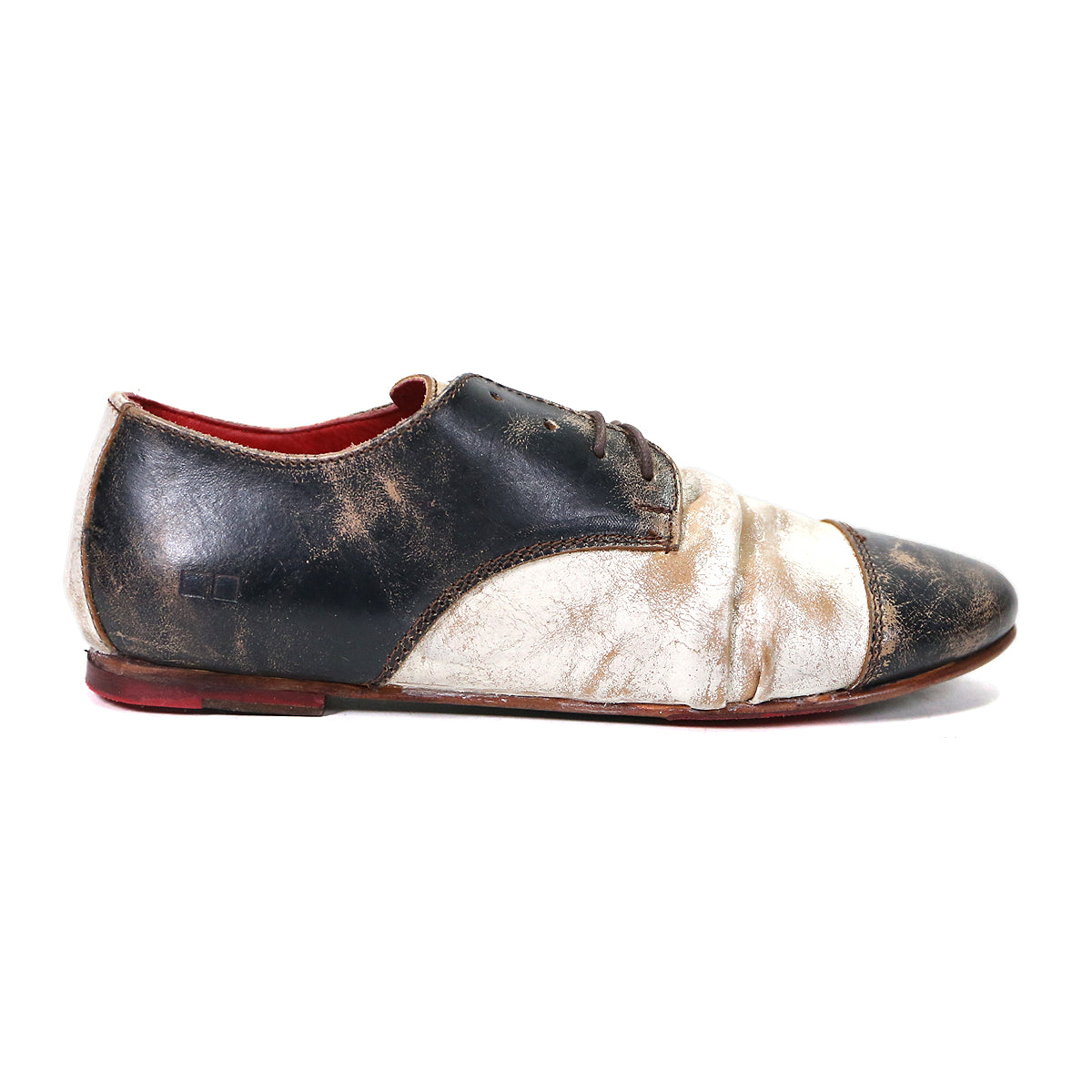 Single worn-out Bed Stu Rumba II black and white leather shoe with red interior, 1920s wingtip design, isolated on a white background.