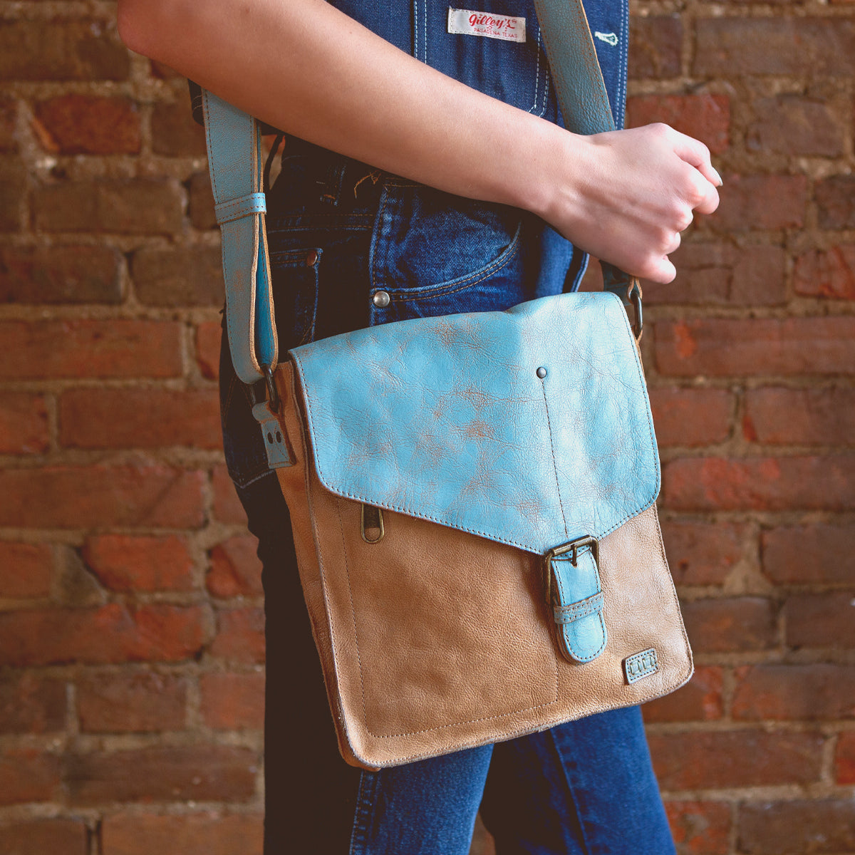 A woman is holding a Bed Stu Venice Beach, a vintage-inspired leather crossbody bag.