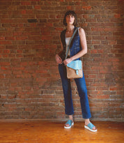 A woman standing in front of a brick wall with a vintage-inspired masterpiece, the Venice Beach by Bed Stu.