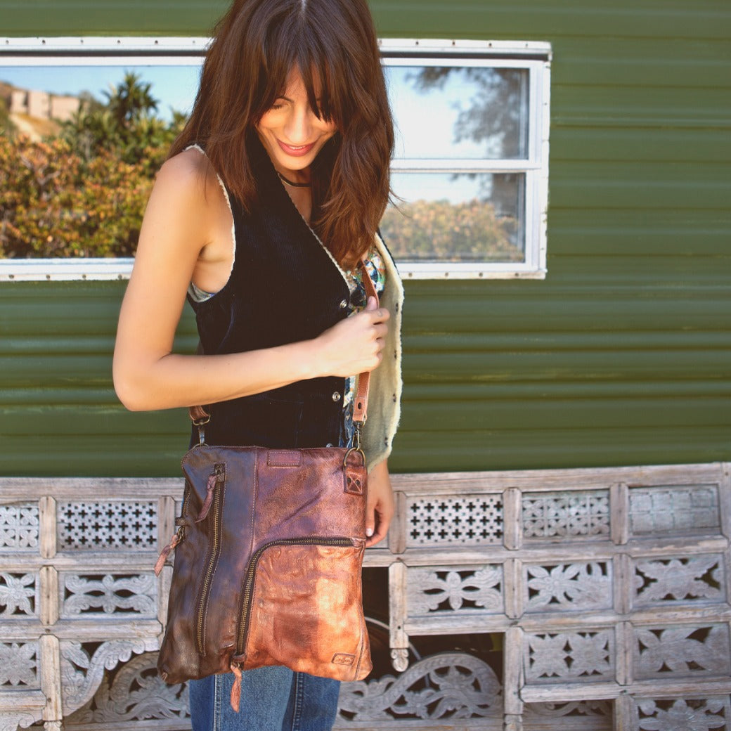 A woman is standing in front of a trailer holding a Bed Stu bag.