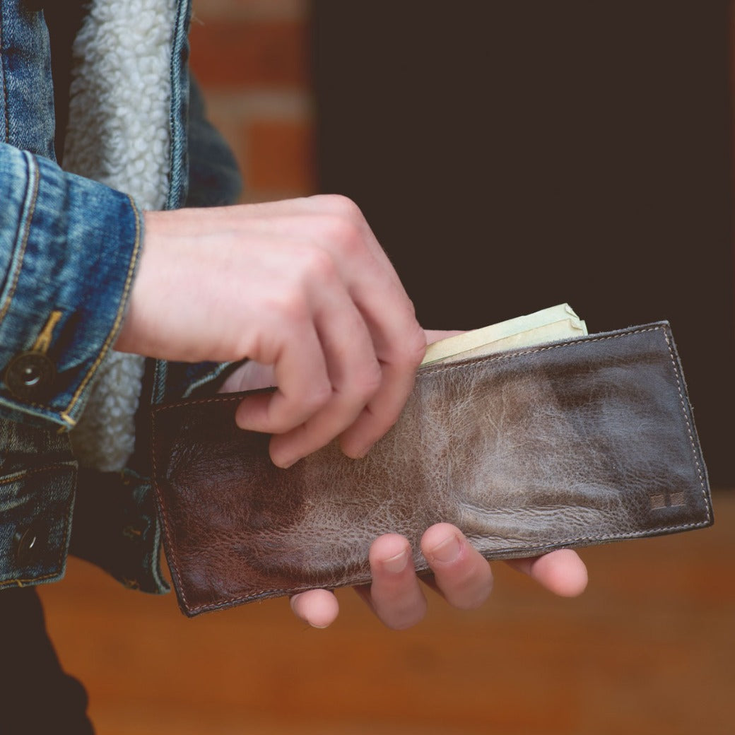 A person holding a Bed Stu brown leather Amidala wallet.