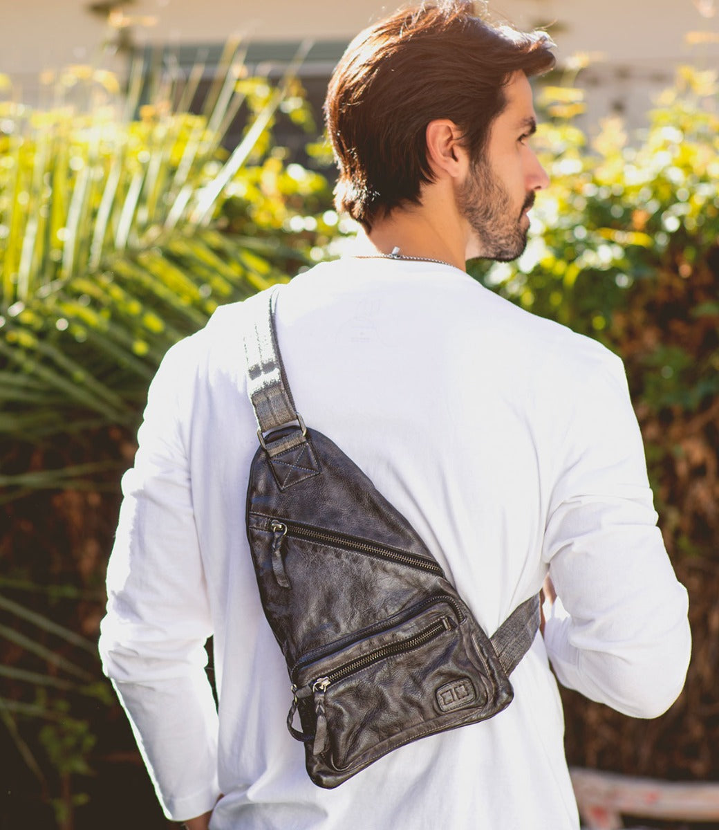 A man wearing a black leather Andie sling bag from Bed Stu.