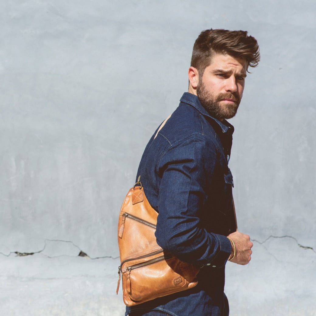 A man with a beard carrying an Andie tan leather sling bag by Bed Stu.