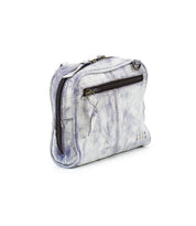 The "Capture" bag by Bed Stu is a compact, textured silver leather handbag featuring a front zippered pocket and two side studs. With artisan-made finishes, it exudes elegance against a plain white background.