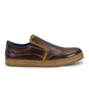 Introducing the Freestyle by Bed Stu, a brown leather slip-on shoe with a tan rubber sole and yellow trim. This side profile view showcases its casual sophistication, highlighted by the meticulous leather detailing.