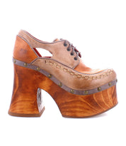 The Karaoke by Bed Stu is a uniquely designed leather shoe featuring laces, metal rivet accents, and a chunky wooden platform heel inspired by the 70s era.