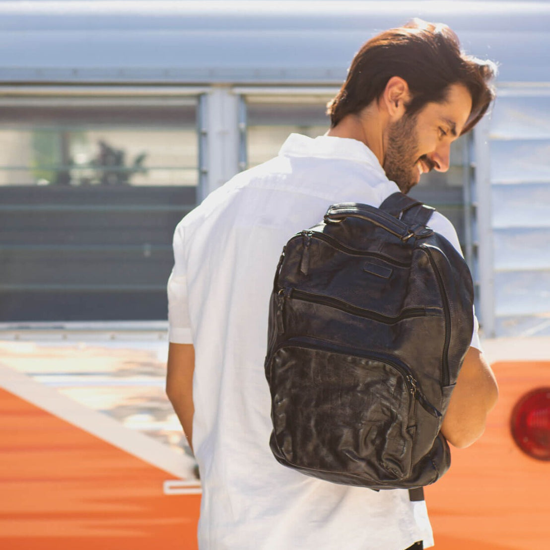 A man with a Bed Stu backpack in front of a camper van.
