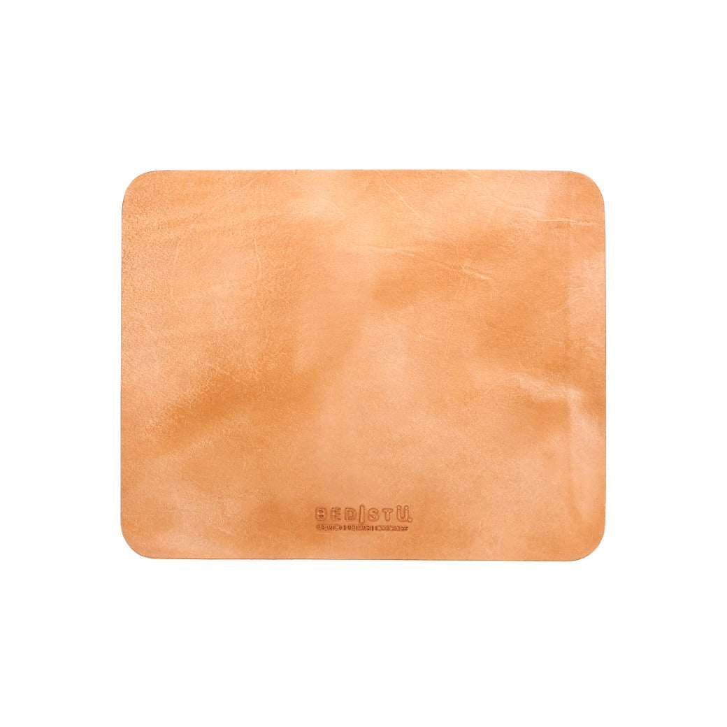A rectangular, light brown leather mouse pad with a smooth surface, rounded corners, and an embossed Bed Stu brand name near the bottom edge. This curated workspace essential, the Launcher Mouse Pad, features a suede underside for added grip.