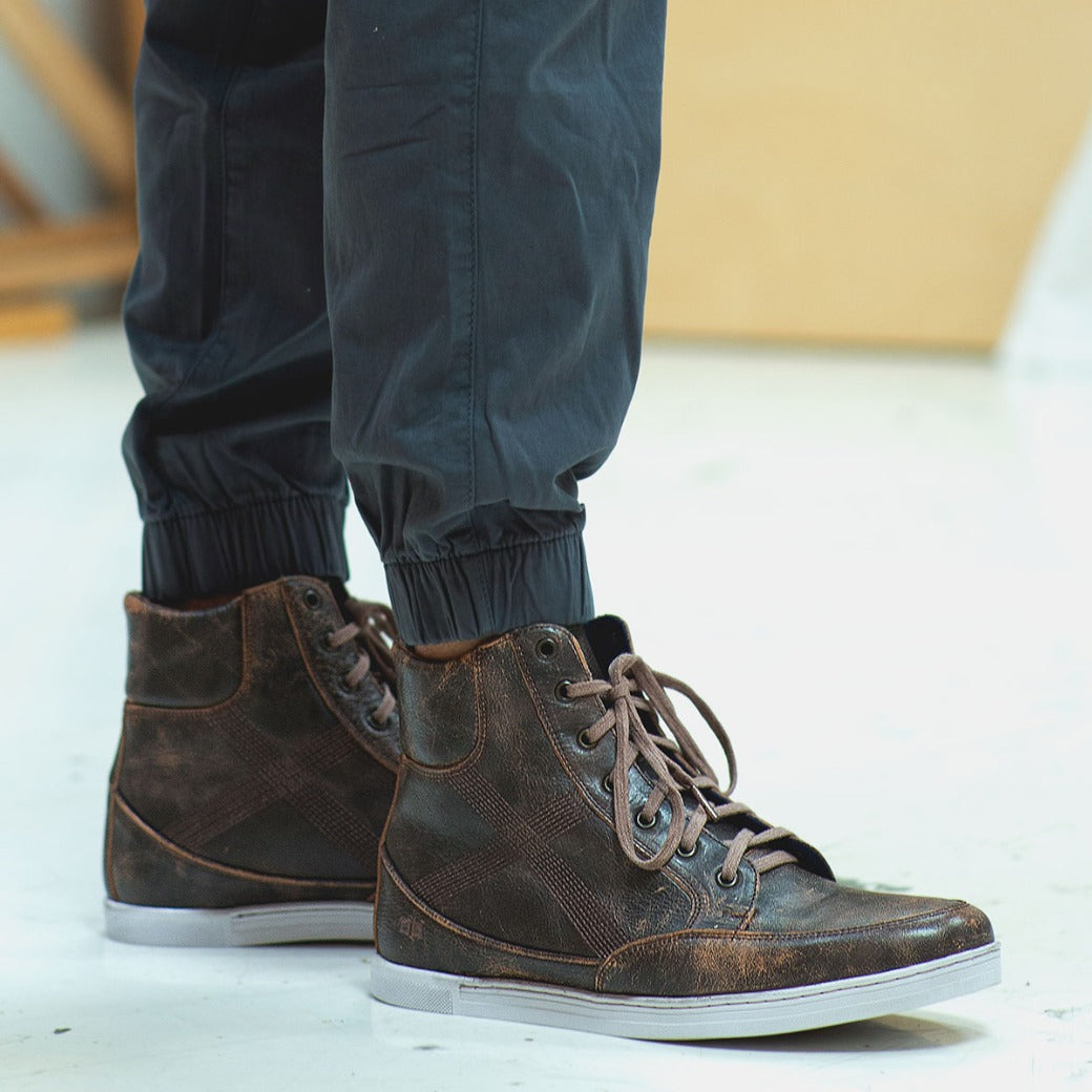 A man wearing a pair of Bed Stu Lordmind brown leather sneakers.
