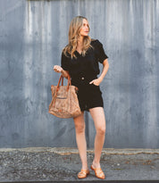 A blonde woman in black shorts and a Bed Stu Mayra tote.