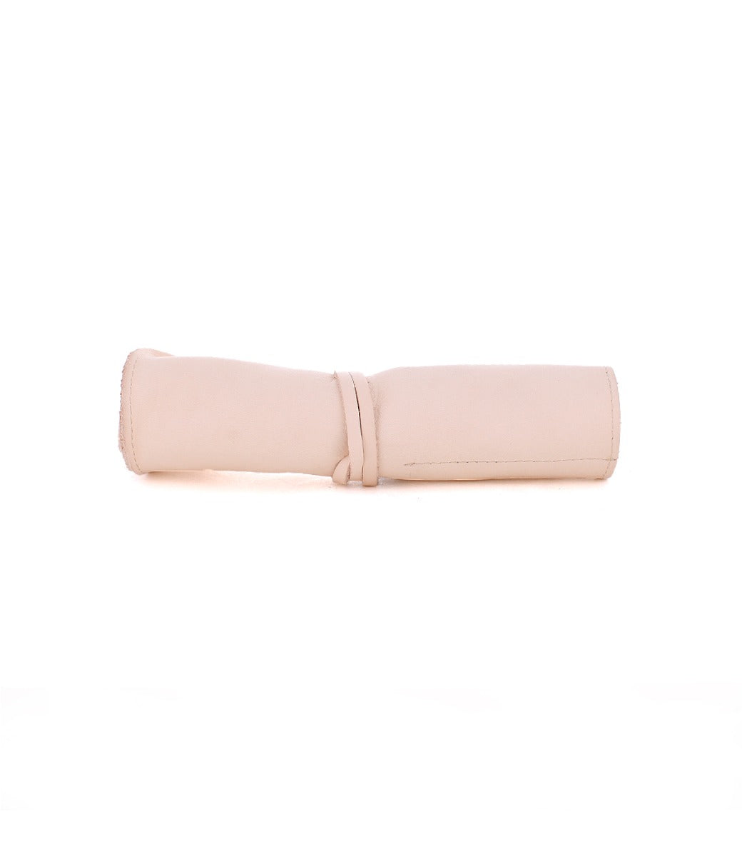 A rolled-up, light beige Prepped Leather Wrap from Bed Stu, designed to hold artist tools, with a simple leather tie closure, positioned on a plain white background.