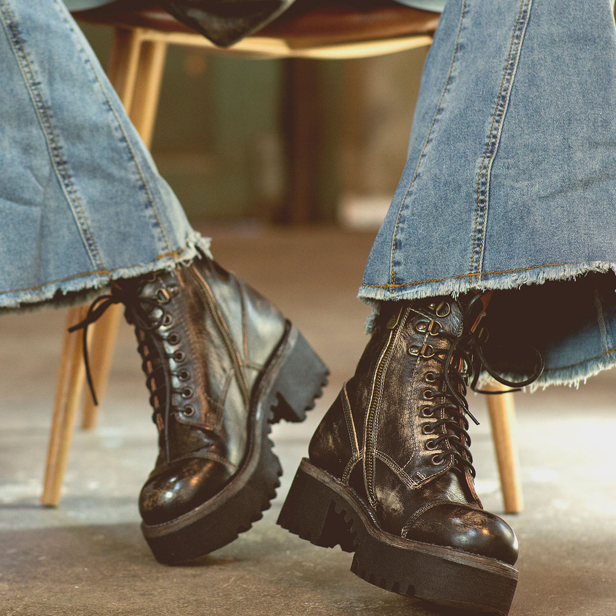 A woman is sitting on a chair wearing Bed Stu Prudence Hi chunky platform combat boots.