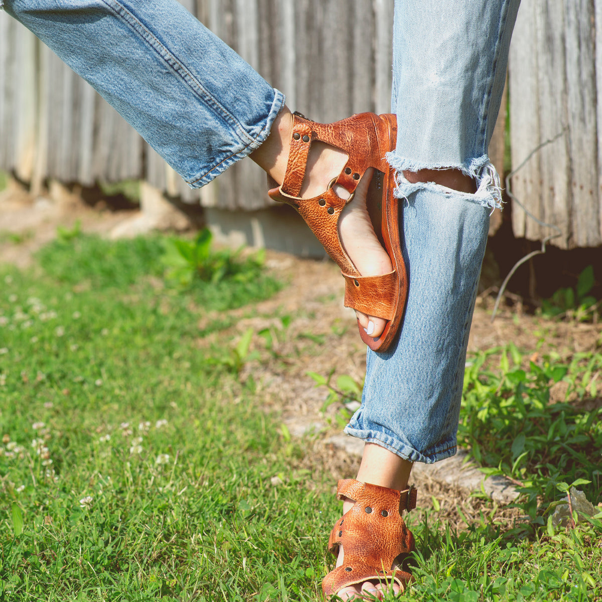 A woman wearing Voleta Bed Stu sandals in front of a wooden fence.